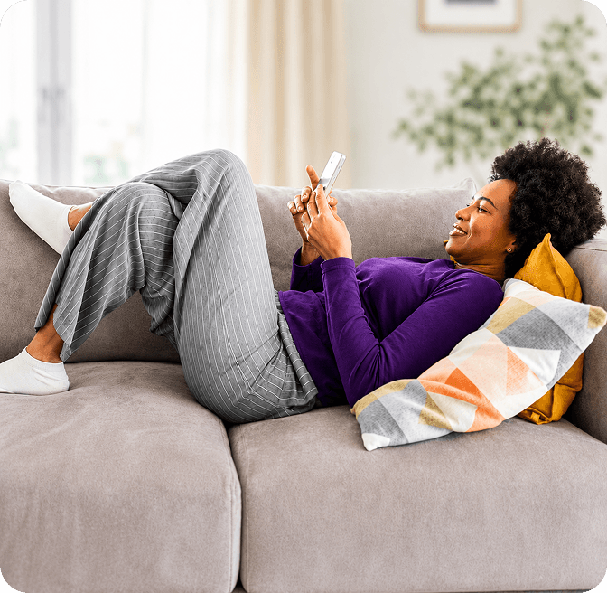 Woman on a couch using her phone with the Raiz App